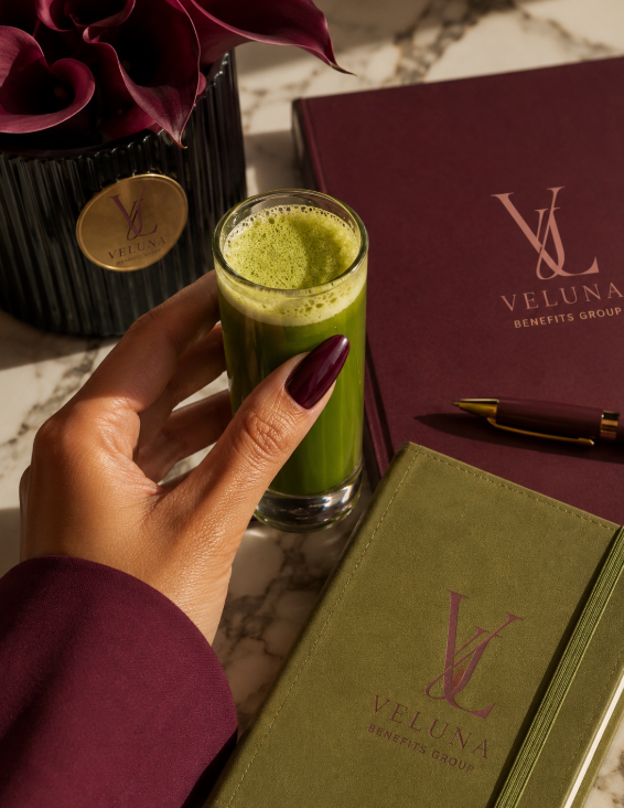 VELUNA Benefits Group branded notebook, planner, and wellness drink in burgundy and olive tones